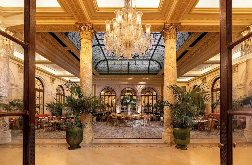 The Palm Court dining room inside The Plaza Hotel with chandelier and palms — public space near the Gossip Girl Oak Room location in New York